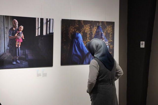 Sanat sergisi görünen kadın izleyici, çerçevede portre ve yüz detaylarıyla fotoğraflar.