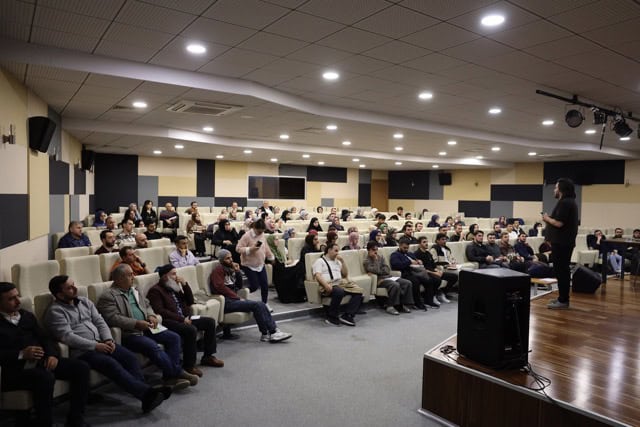 Etkinlik katılımcıları ve sunucu, toplantı ve konferans ortamı.