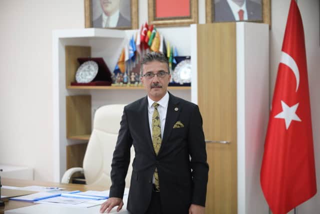 İmza Lideri, resmi ofiste Türk bayrağı ve çeşitli ödüllerle çevrili.